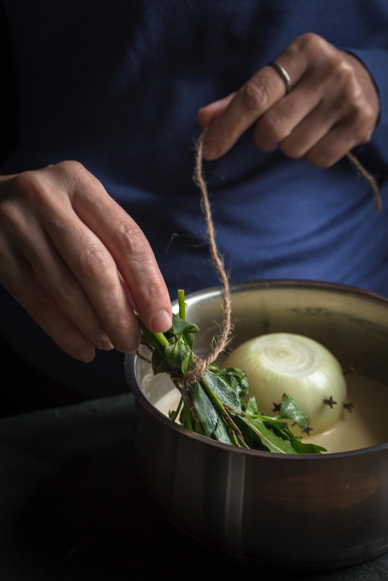 Chef arranging a plated dish with herbs and ceramic